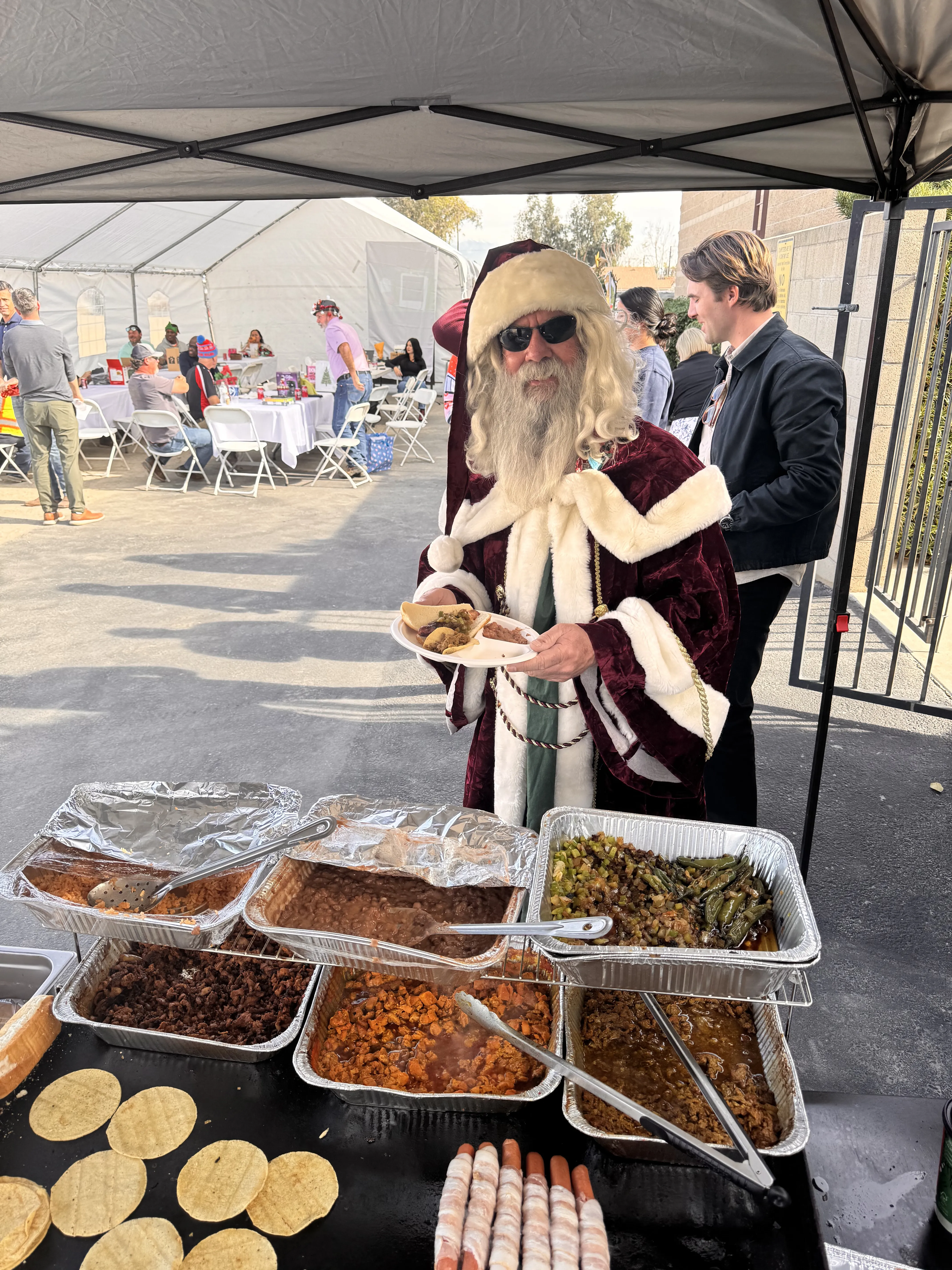 Santa Claus enjoying the Mr. Hot Bunz taco and bacon dog spread at a holiday company party